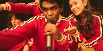 Young people in matching red tracksuits take the microphone to rap